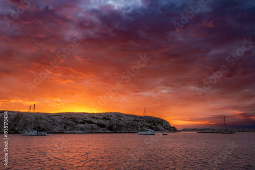 Colorful sunset above sailboats anchored in bay facing Gluppö in Fjällbacka archipelago, Bohuslän, Sweden