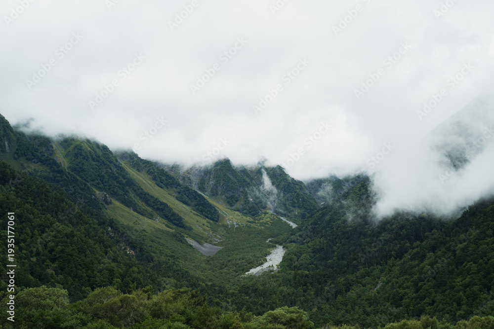 Fototapeta premium Travel to the high mountain peak where fog and mist drift across the landscape, painting the sky with silver light and turning the quiet scenery into radiant sunrise sky.