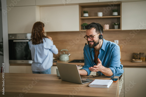 Photos Man on video call working remotely at home kitchen