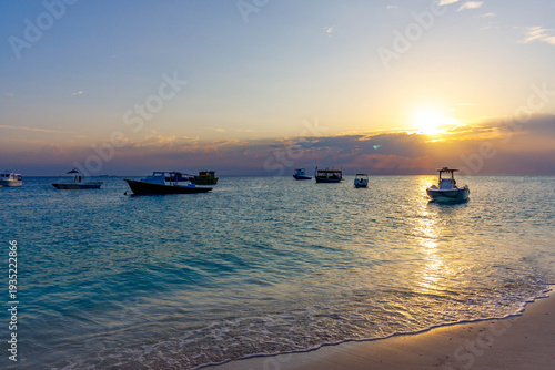 Golden sun dips low over calm turquoise sea