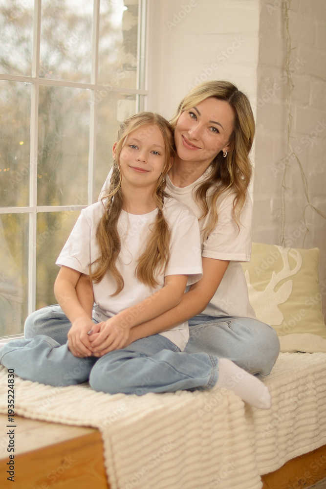 Obraz premium Little girl daughter hugging embracing happy beloved mother with love and tenderness while celebrating special occasion together at home, child wishing happy birthday to mom, greeting with Mothers Day