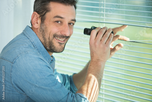 Принти на полотні excited man spying through the window blinds with binoculars