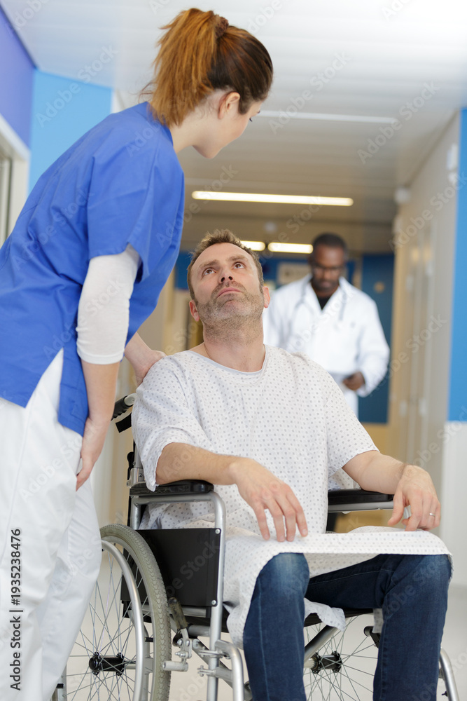 Obraz premium friendly nurse supporting smiling paralyzed man in a wheelchair