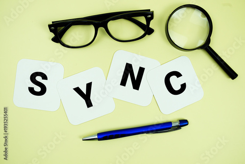 Фотография SYNC alphabet letters with magnifying glass, eye glasses and pen on yellow backg