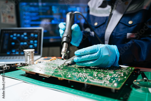 Senior technician performing PCB soldering and diagnostics with multimeter in electronics lab, showcasing hardware engineering