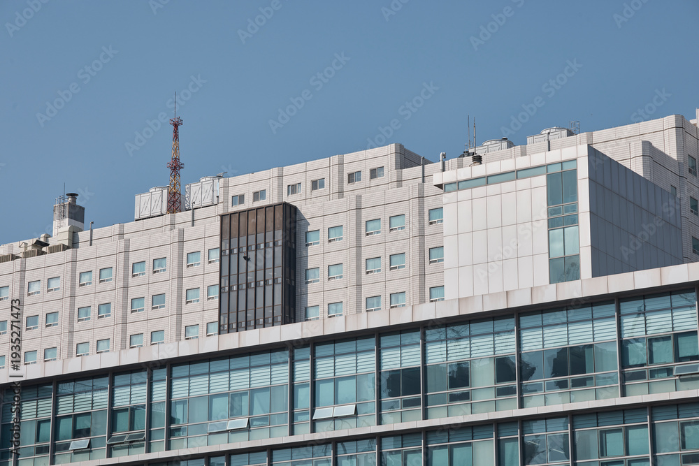 Fototapeta premium Modern building exterior facade with windows under clear sky.