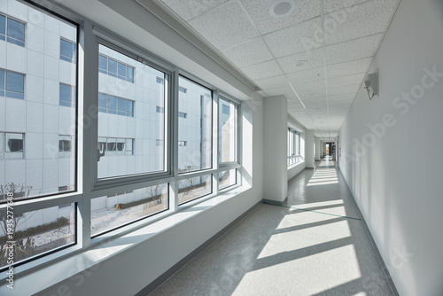 Glass corridor or skybridge with strong sunlight and shadows.