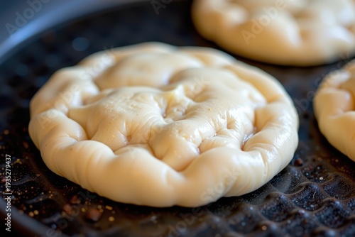 A close up of a perfectly round Jamaican Bammy (cassava bread) being flipped on a hot griddle.