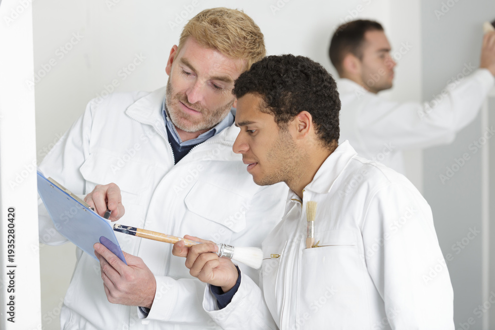 Obraz premium two professional factory painters workers looking documents