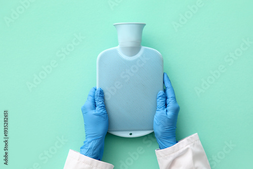 Canvas Print Female doctor's hands with hot water bottle on turquoise background