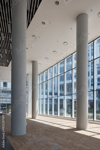 Modern lobby with tall columns and glass facade, bright architecture.