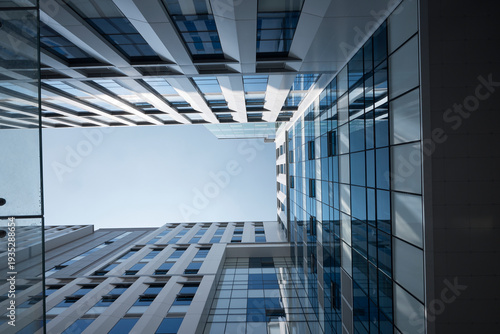 Looking up between modern high-rise buildings with geometric lines and urban architecture perspective.