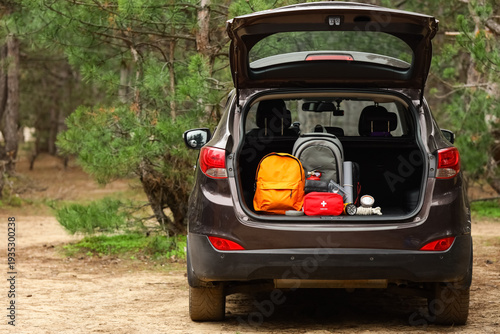 Fotografi Emergency backpacks with necessities in open car trunk outdoors