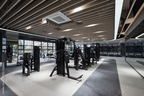 Empty modern fitness gym interior with cardio machines and strength training equipment.