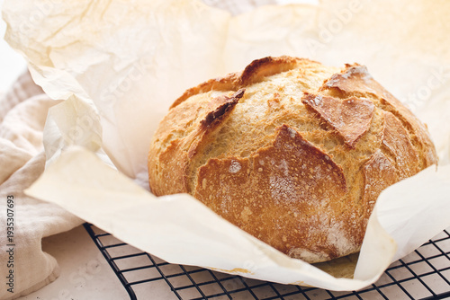 Round sourdough loaf resting on black wire cooling rack with beige linen towel. Perfect for baking, food blogs, and culinary projects