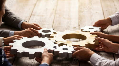 Fotografie Diverse group of hands assembling interlocking silver and gold gears on a wooden table, symbolizing collaboration, teamwork, and shared goals in business