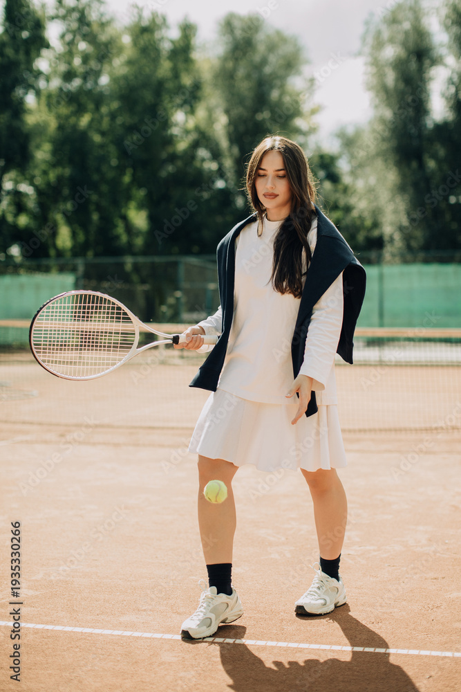 Obraz premium Young woman playing tennis on a clay court