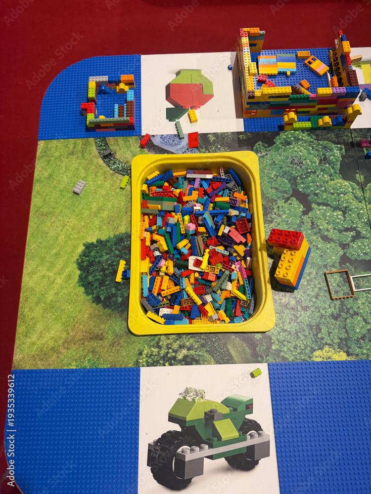 Fototapeta premium Colorful building bricks in yellow bin on play mat