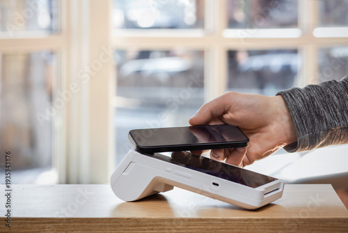 Payment Terminal. Contactless Mobile Payment at POS Terminal. Hand Holding Smartphone over Modern Point-of-sale Terminal. Mobile Electronic Payment Terminal.