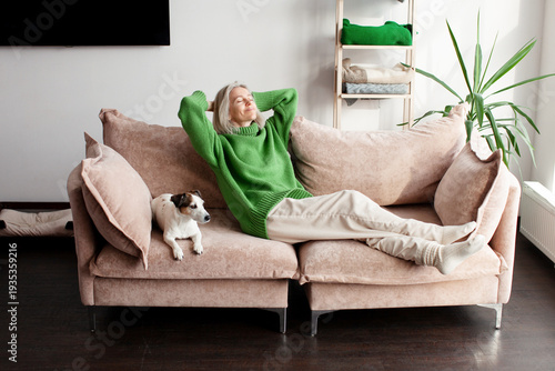 Картината върху платно Mindful happy woman homeowner daydreaming in comfortable sofa, sleeping with fol