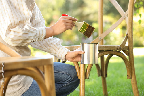 Woman painting chair in garden