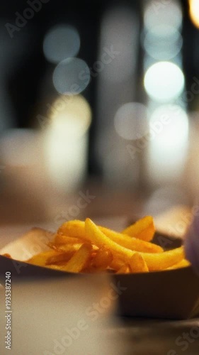 Hands skillfully serve steaming fries using wooden spoon in cozy kitchen filled with warmth of comfort food, inviting friends to gather share delightful meal together, savoring joy of homemade cooking