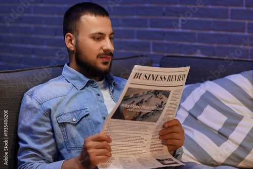 Young man reading newspaper...