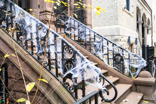 Brownstone stoops in Manhattan, New York, decorated with white spider web decorations for Halloween.Classic Upper West Side brownstones with decorated stoops and railings.
