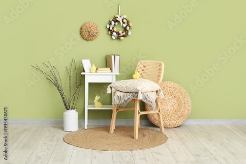 Chair, coffee table and can with willow branches in room decorated for Easter celebration