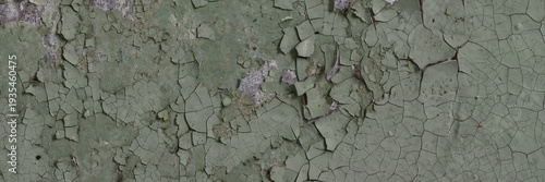 Peeling paint on the wall. Panorama of a concrete wall with old cracked flaking paint. Weathered rough painted surface with patterns of cracks and peeling. Wide panoramic texture for grunge background