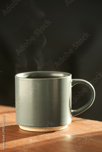Green mug of hot tea on woo...