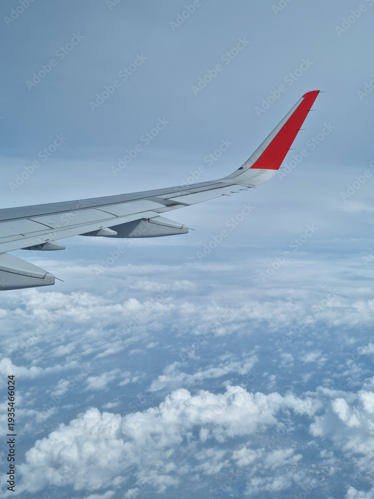 Fototapeta premium Airplane wing through the clouds in the sky.
