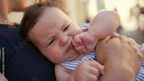 Canvas Print Baby awake stretching body while lying on mother’s lap outdoors, hands reaching