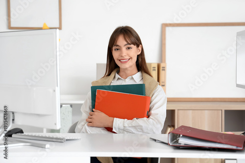 Young businesswoman with folders at desk in office