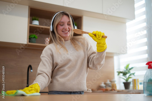 Konstfotografi Woman cleaning kitchen while listening to music and singing with spoon