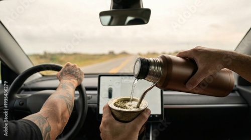 Close up of a person pouring hot water from a thermos into a traditional yerba mate gourd inside a modern car during a road trip.