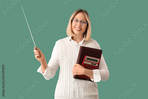 Mature female math teacher with pointer, calculator and folder on green backg...
