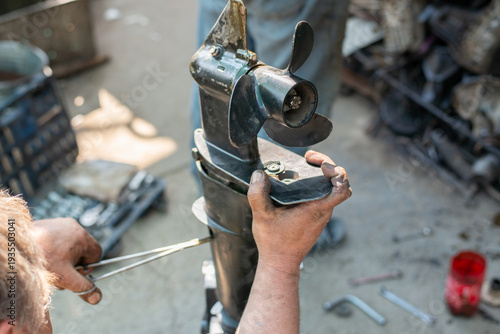Quadro su tela The hands of a master auto mechanic repair a gasoline outboard marine engine