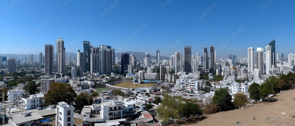 Fototapeta premium A wide angle shot shows buildings, a golf course, and green grass near houses under a clear blue sky