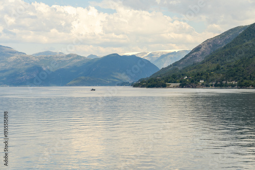 Wallpaper Mural View of tranquil waters reflect the sky as mountains rise in the distance, a boat gliding through the serene landscape, Hardanger Fjord, Vestland, Norway. Torontodigital.ca