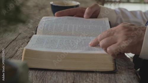 white man's Hands on Open Holy Bible on wooden table Reflecting Faith at indoors