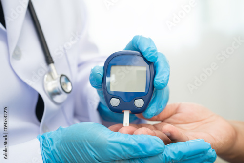 Asian doctor using digital glucose meter for check sample blood sugar level to treatment diabetes.
