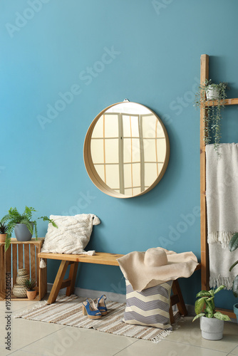 Wooden bench with pillows, female accessories and mirror near blue wall in hall