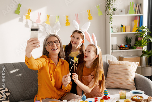 Happy intergenerational family celebrating Easter, taking a selfie with bunny ears