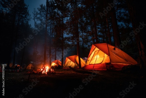 Camping tents lit up at night in forest with campfire