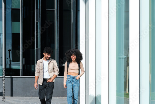 Foto Young multiracial students walking alongside university building