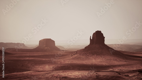 A breathtaking desert scene captured during sunset, featuring majestic rock formations rising from the arid ground. The warm glow enhances the natural beauty of this remote landscape.