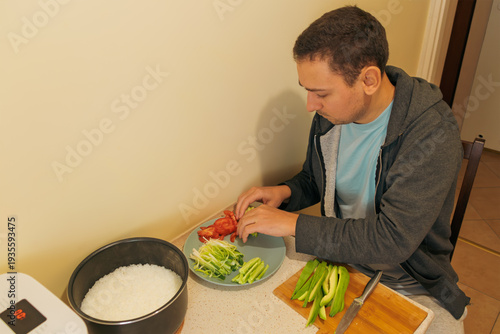 Bilde på lerret Man slicing vegetables and arranging plate on kitchen counter