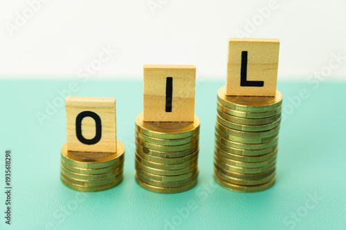 Oil price increase concept, expressed with stacks of coins and wooden alphabet.