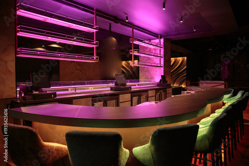 Modern empty bar interior with pink neon lights green velvet chairs and curved counter